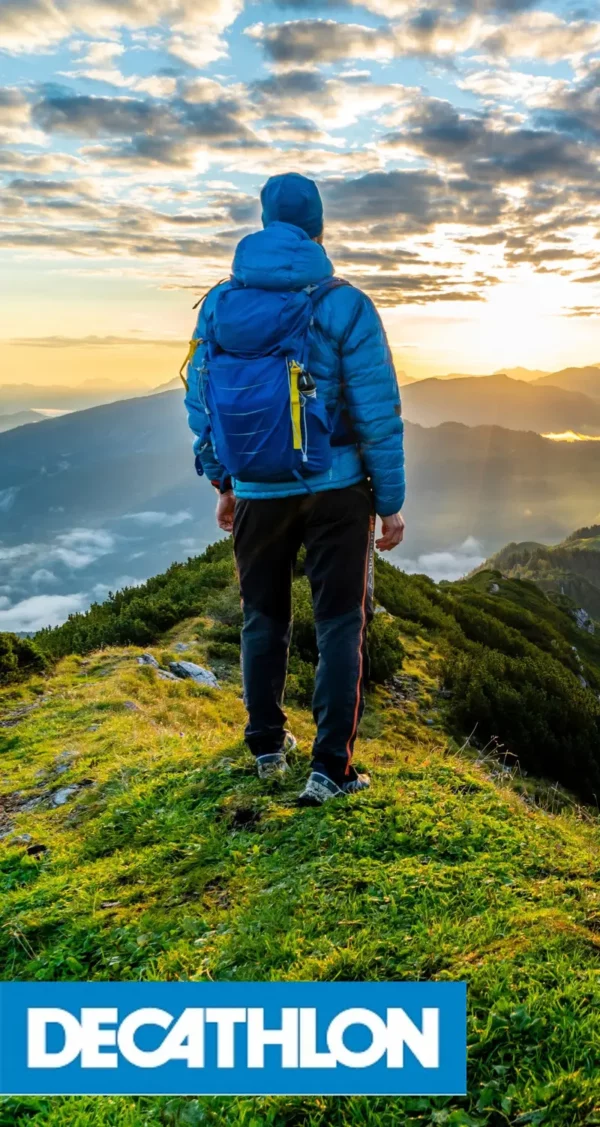 as Bild zeigt eine Person in Outdoor-Kleidung, die auf einem Berggipfel den Sonnenaufgang betrachtet. Es vermittelt Abenteuerlust, Freiheit und Naturverbundenheit, unterstrichen durch das Decathlon-Logo.