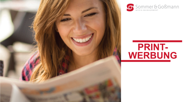 Lächelnde Frau liest eine Zeitung und schaut nach unten.