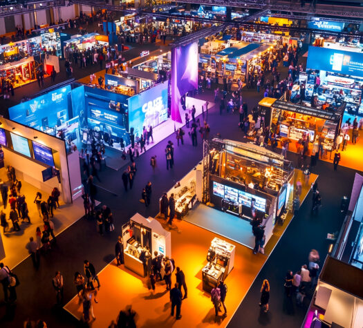 Aerial view of a bustling trade show or exhibition with numerous booths, attendees, and vibrant lighting creating a dynamic atmosphere of commerce and networking Aerial view of a bustling trade show or exhibition with numerous booths, attendees, and vibrant lighting creating a dynamic atmosphere of commerce and networking